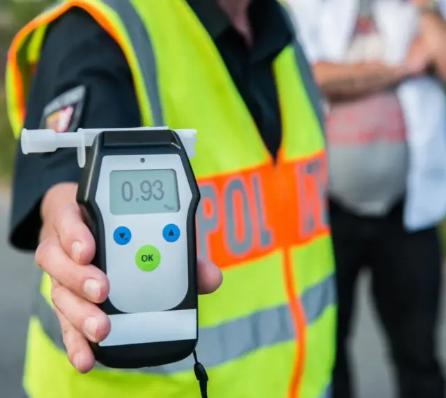Policjant pokazuje alkomat z wynikiem 0.93 promile alkoholu. Kontrola drogowa trwa.