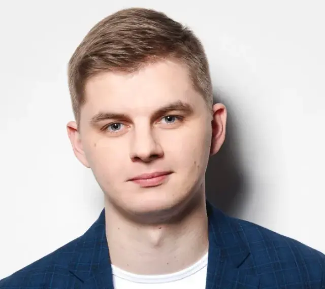 Młody mężczyzna w niebieskiej marynarce w kratę, gotowy do występu. Polski stand up w jego wykonaniu to gwarancja dobrej zabawy.