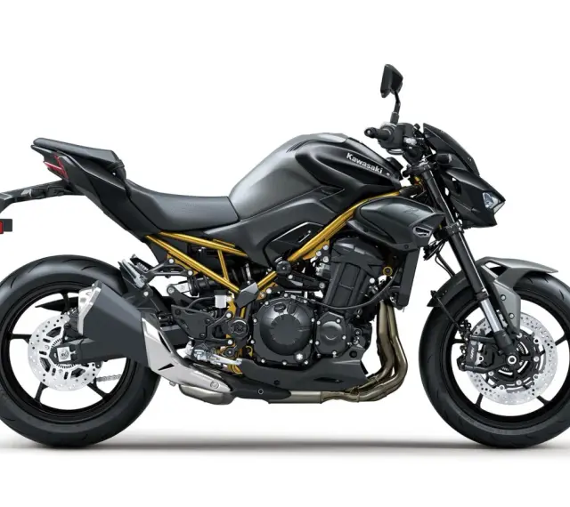 Stylowy, czarny Kawasaki Z900 z widoczną złotą ramą, gotowy na podbój dróg.
