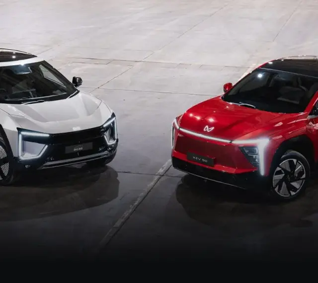 Dwa futurystyczne SUV-y, biały i czerwony, marki Mahindra, prezentują nowoczesny design z ostrymi liniami i LED-owym oświetleniem.