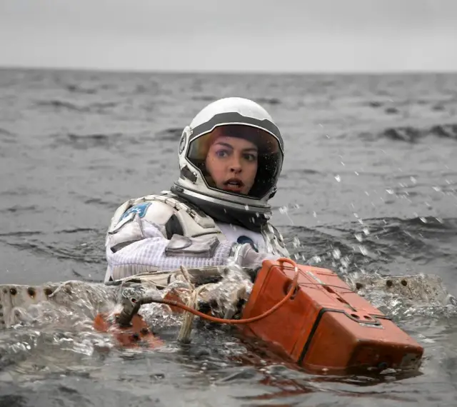 Astronautka w skafandrze z filmu Interstellar 2 w wodzie, z pomarańczowym urządzeniem.
