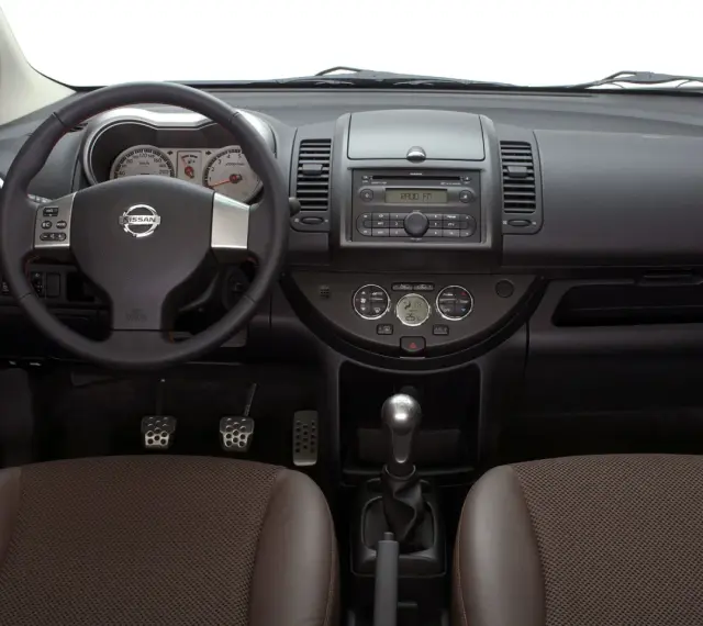 Wnętrze Nissan Note E11: kierownica, deska rozdzielcza z radiem i zegarami, dźwignia zmiany biegów, fotele.