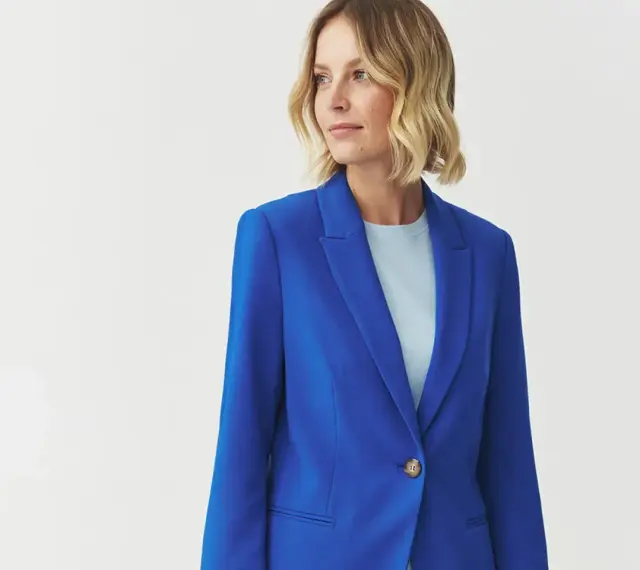 Kobieta w eleganckim, niebieskim żakiecie. Kolor kobaltowy a chabrowy idealnie podkreśla jej urodę.