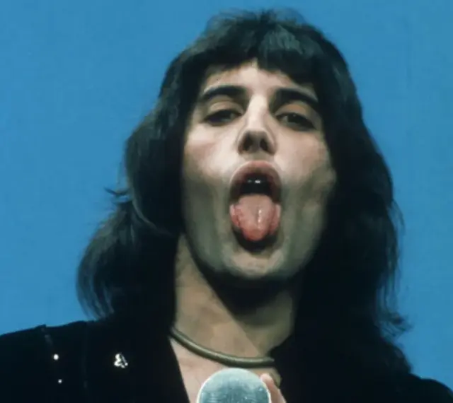 Freddie Mercury z wyciągniętym językiem, śpiewający do mikrofonu. W jego oczach widać pragnienie, by **break free**.