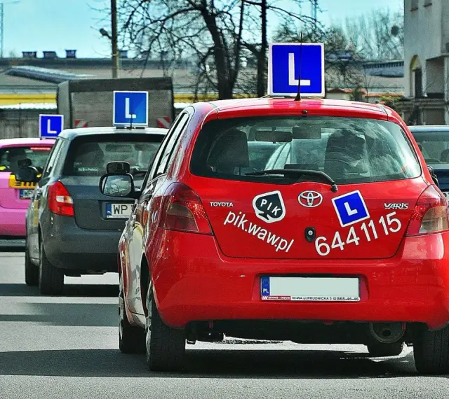 Czerwony samochód nauki jazdy z literą "L" na dachu. Zastanawiasz się, ile zarabia instruktor jazdy?
