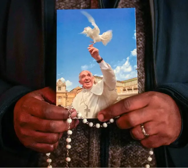 Dłonie trzymają obrazek z Papieżem Franciszkiem wypuszczającym gołębicę. To inspiracja z cytatów papieża franciszka.