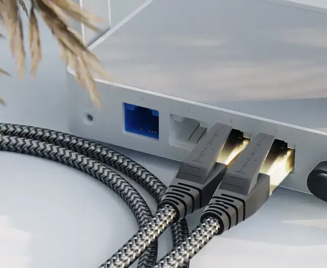 Zwei geflochtene ethernet-Kabel stecken in einem weißen Router, daneben ein schwarzes Stromkabel.