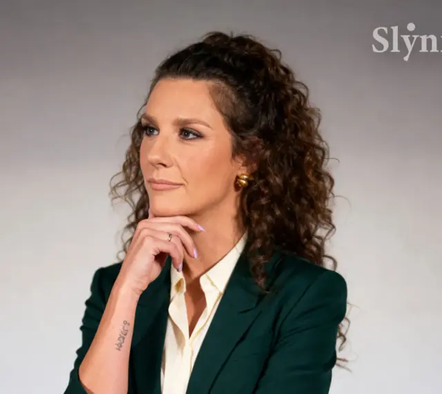 Wiolka Walaszczyk, w wieku około 40 lat, w eleganckim zielonym żakiecie, zamyślona.