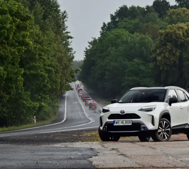 Biały crossover na poboczu drogi, w tle sznur samochodów i zielone drzewa. Trasa z Warszawy do Szczecina, ile km?