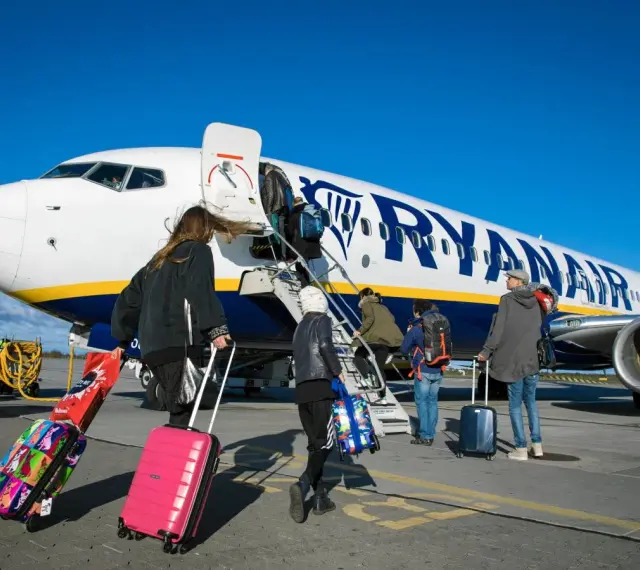 Ludzie z bagażami wsiadają do samolotu Ryanair. Może to być początek podróży lub sytuacja, gdy ktoś planuje **Ryanair zwrot biletu**.