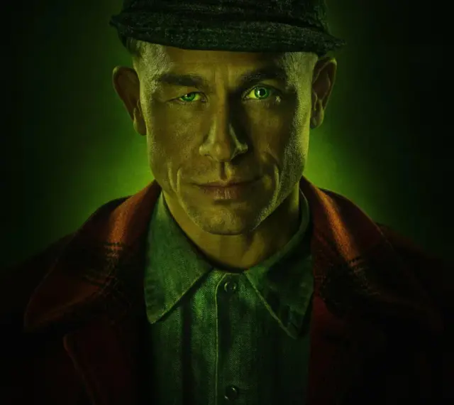 Mężczyzna z zielonymi oczami i czapką na głowie, w tle zielona poświata. Zapowiada mroczne seriale kryminalne Netflix.