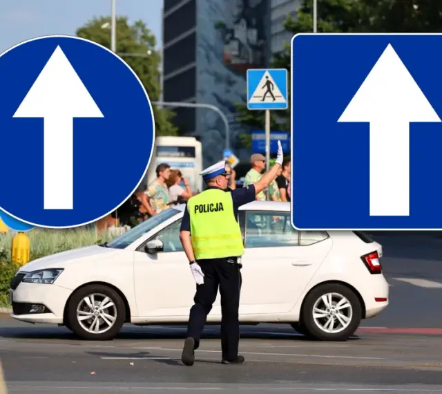 Policjant kieruje ruchem przy znakach droga jednokierunkowa. Biała Skoda czeka na sygnał.