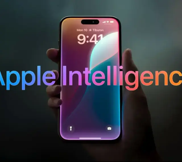 Dłoń trzyma smartfon z ekranem blokady, na którym widnieje napis "Apple Intelligence" w tęczowych barwach.