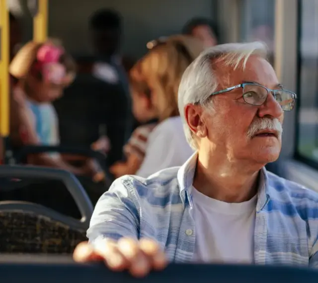 Starszy pan w okularach, podróżujący autobusem w Szczecinie, zastanawia się, czy 70 latek płaci za komunikację miejską.
