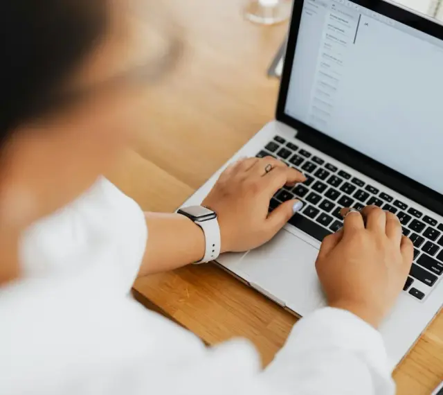 Kobieta pisze na laptopie, na ekranie widać artykuł po niemiecku.