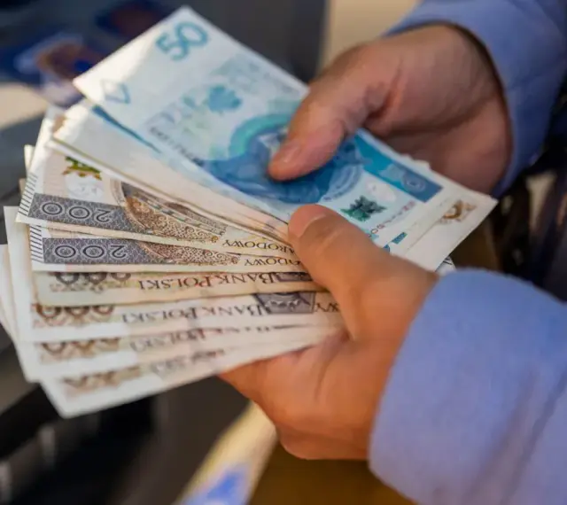 Ręce trzymające stos banknotów 200 zł i 50 zł. Zastanawiasz się, renta alkoholowa ile wynosi?