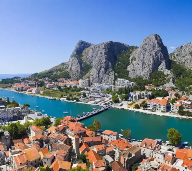 Widok na miasto Omiš w Chorwacji, gdzie rzeka Cetina wpada do morza. Piękne, turkusowe morze i góry.