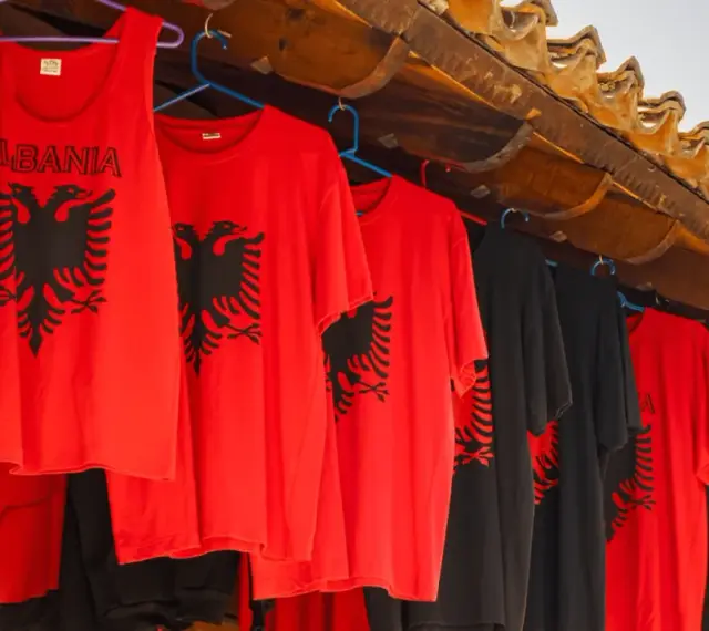 Czerwone i czarne koszulki z dwugłowym orłem, idealne pamiątki, co można przywieźć z Albanii samolotem.