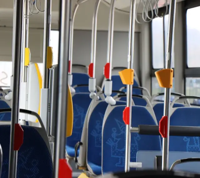 Wnętrze autobusu 139 z niebieskimi siedzeniami i metalowymi poręczami.