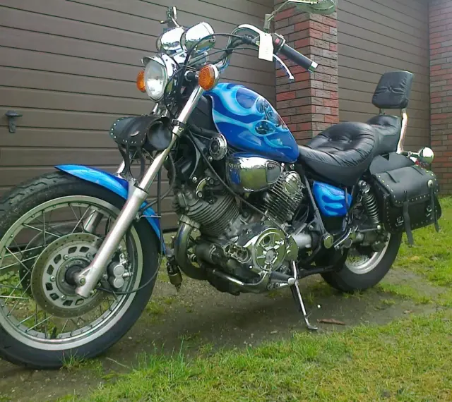 Błękitny motocykl Yamaha Virago 1100 z płomieniami, skórzanymi sakwami i oparciem. Wady i zalety tego klasyka do rozważenia przed zakupem.