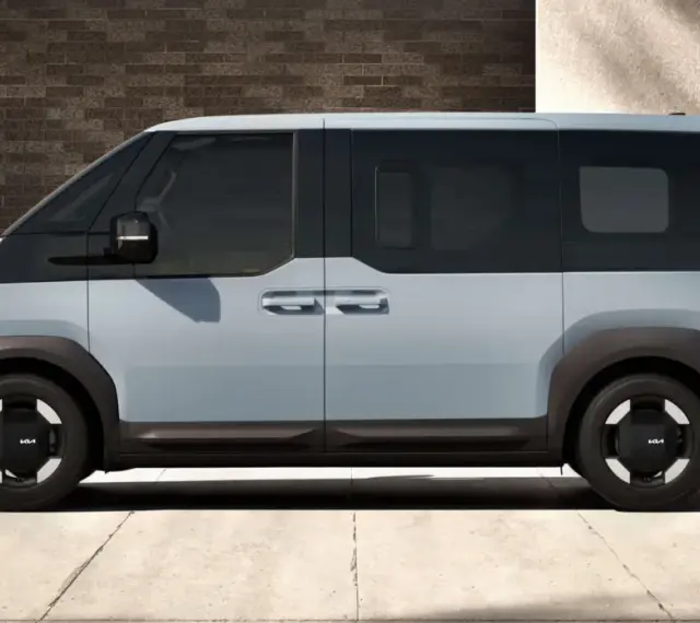 Jasnoszary elektryczny van Kia PV5 z czarnymi akcentami, widziany z boku.