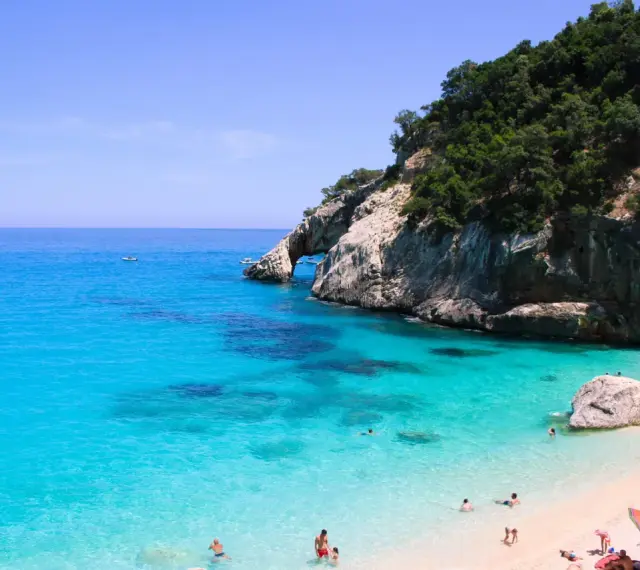 Cala Goloritze: turkusowa woda, skaliste klify i plażowicze cieszący się słońcem.