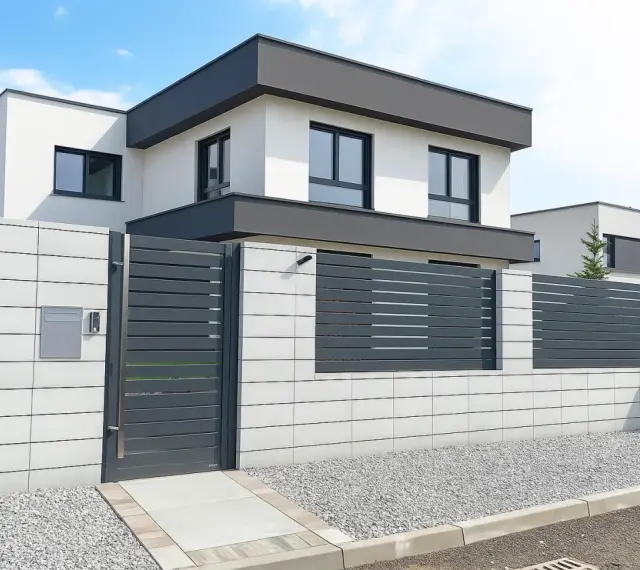 Nowoczesne, biało-szare ogrodzenie z elementami metalowymi i betonowymi, idealnie pasujące do minimalistycznej architektury domu.