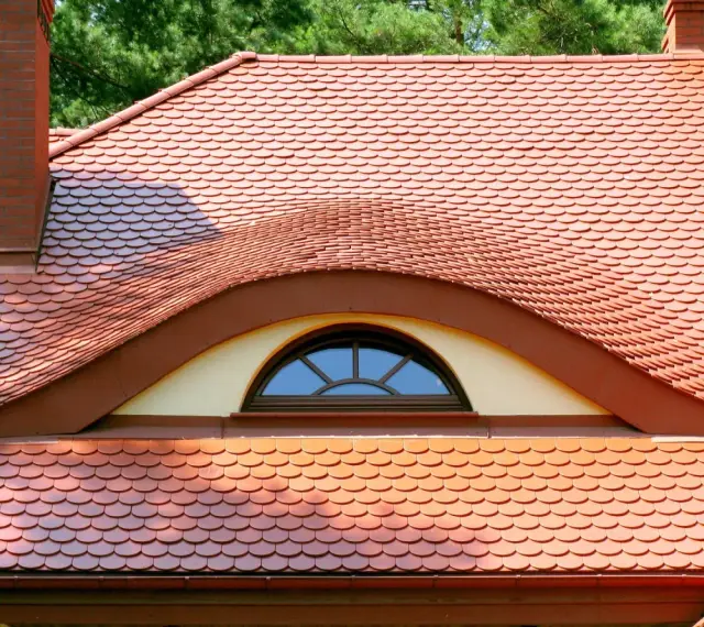Ceglana dachówka ceramiczna w kształcie rybiej łuski, z ozdobnym lukarną. Idealna, by stworzyć stylowy dach.