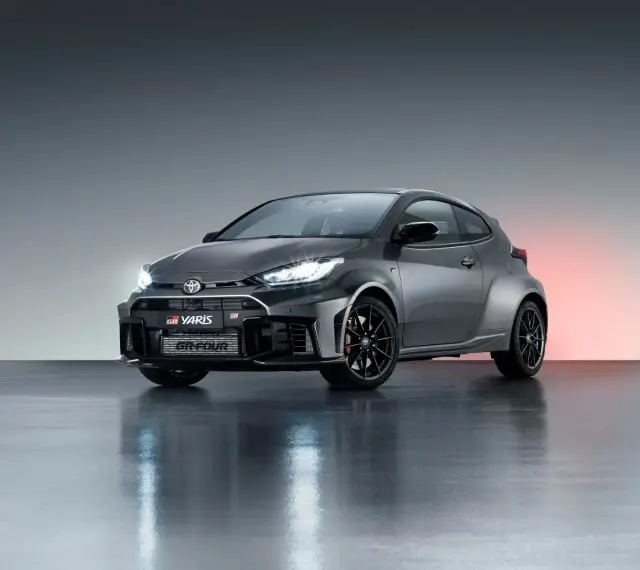Szary Toyota GR Yaris GR-FOUR z agresywnym przednim zderzakiem i czarnymi felgami, gotowy do podboju dróg.