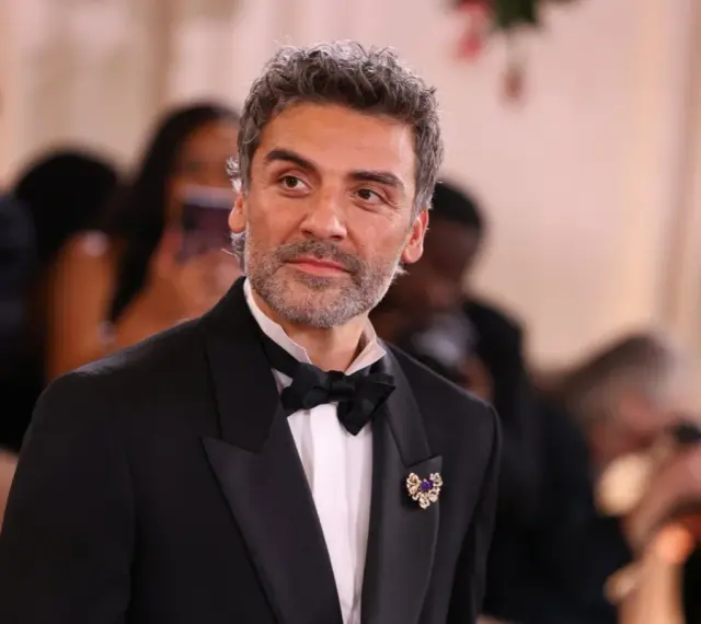 Oscar Isaac w eleganckim smokingu, gotowy na premierę swoich najnowszych filmów, seriali i programów.