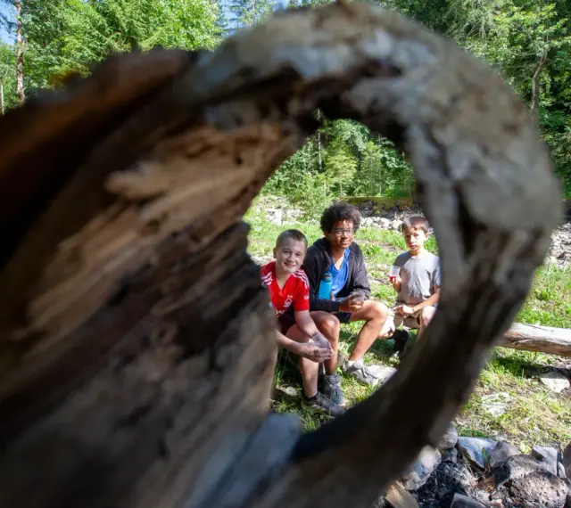 Trois enfants profitent d'une pause en forêt, rappelant l'importance du respect des locaux et de la nature.