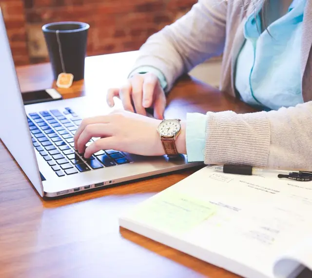 Kobieta pracuje na laptopie, analizując dokumenty. Może to być związane z rozliczeniem podatku od wzbogacenia.