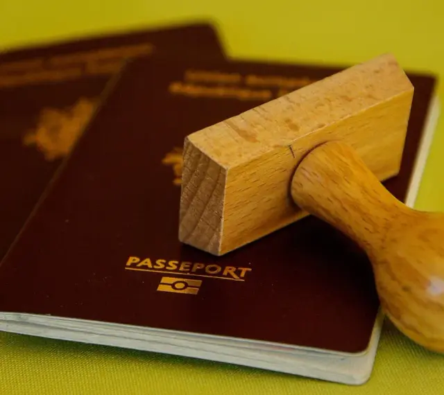 Drewniany stempel nad paszportem, gotowy do pieczętowania. Marzysz o podróży? Biuro paszportowe Lublin pomoże Ci spełnić marzenia.