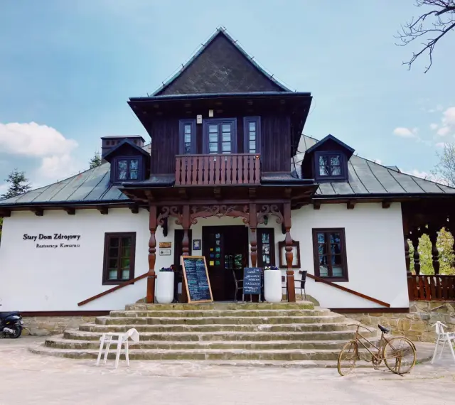 Stary Dom Zdrojowy w Beskidach, z charakterystyczną architekturą i kamiennymi schodami, zaprasza do restauracji.