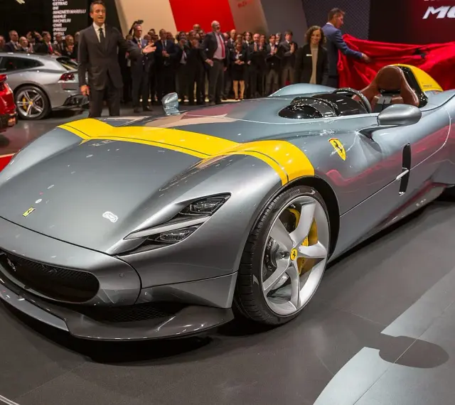Szary Ferrari Monza SP1 z żółtymi pasami, odsłaniany na scenie.