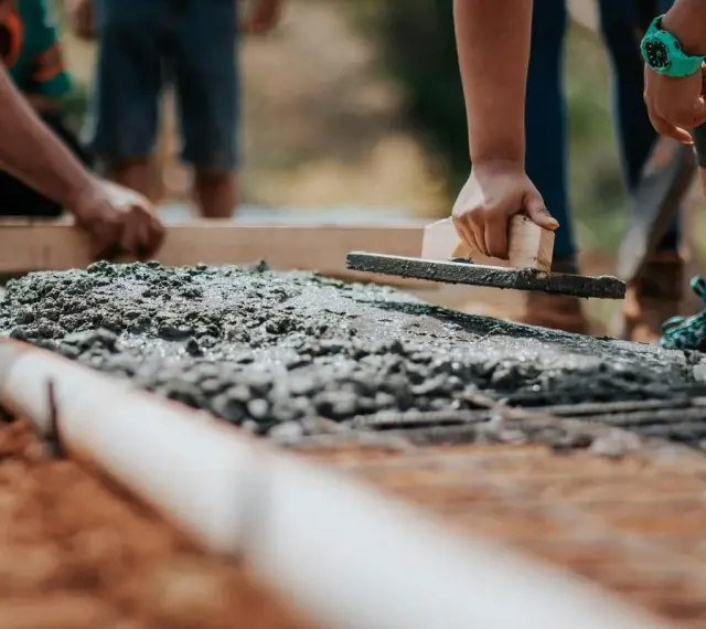 Pracownicy wyrównują świeży beton na fundamencie. Jaki beton na fundament b20 czy b25?