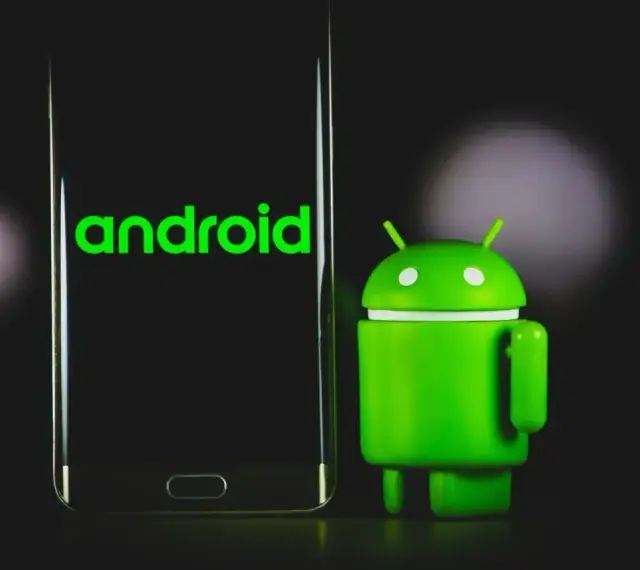 Zielony robot Android obok telefonu z logo Android 13.