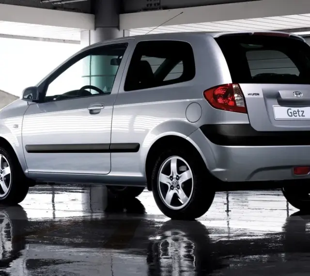 Srebrny Hyundai Getz 1.1 z czarnymi listwami, odbijający się w mokrej nawierzchni pod zadaszeniem.