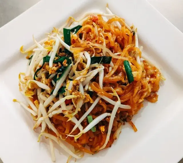 Pyszne danie Pad Thai z makaronem ryżowym, kiełkami fasoli mung, jajkiem i zieloną cebulką, polane charakterystycznym pad thai sosem.