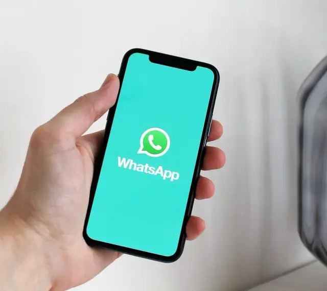 Dłoń trzyma smartfon z logo WhatsApp. Idealne narzędzie do komunikacji, gdy masz internet za granicą.