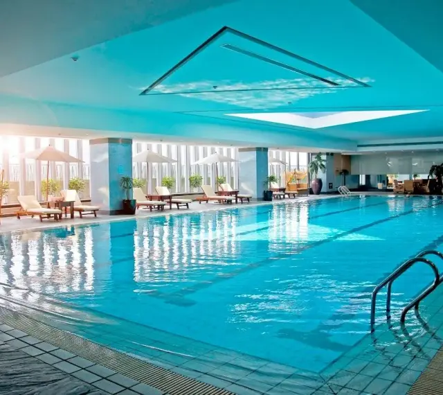 Relaks w hotelu z basenem na Podlasiu. Długi, błękitny basen z leżakami i parasolami, idealny na wakacje.