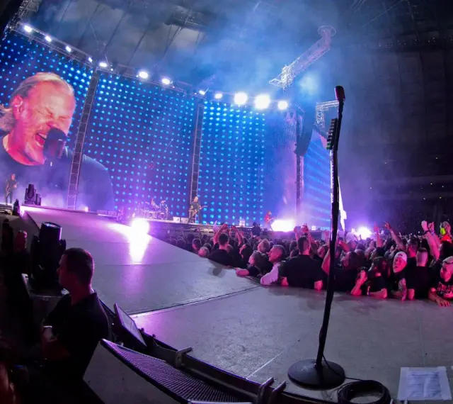 James Hetfield śpiewa na koncercie Metalliki w Warszawie. Tłum szaleje, a gigantyczny ekran pokazuje zbliżenie na wokalistę.