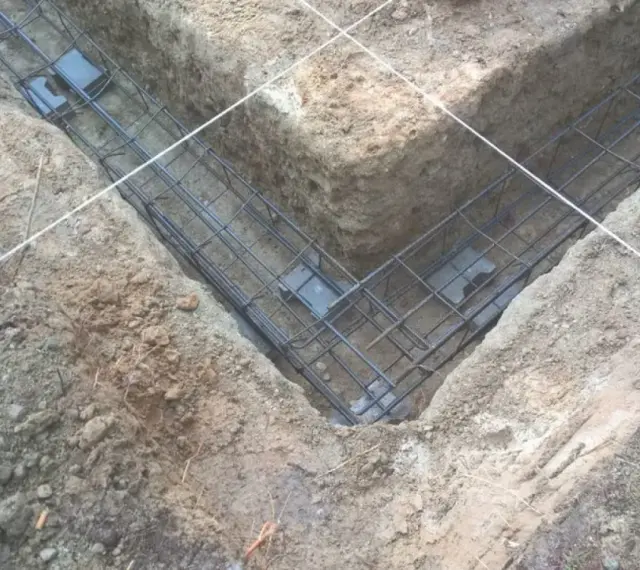 Zbrojenie fundamentów prefabrykowanych w wykopie. Stalowe pręty tworzą siatkę, gotową do zalania betonem.