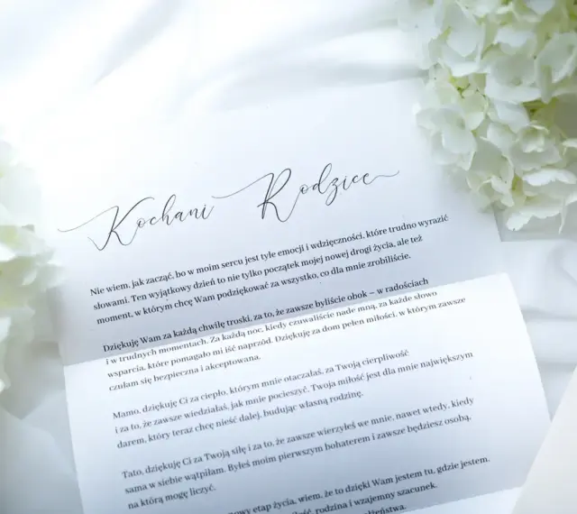 List do rodziców z podziękowaniami. Białe kwiaty i elegancka koperta tworzą tło dla wzruszających słów.