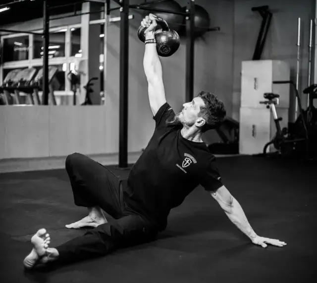Mężczyzna wykonuje ćwiczenia na siłowni z kettlebell.