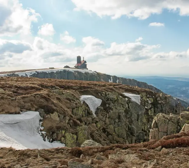 Budynek na szczycie góry w Karkonoszach, z widokiem na dolinę i chmury.