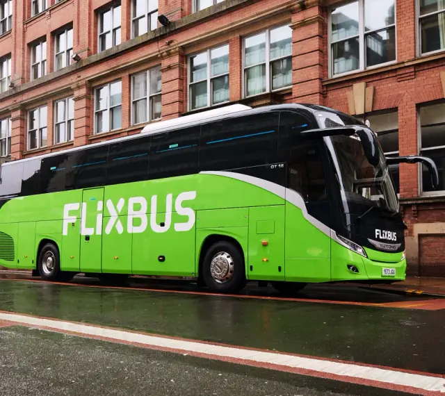 Zielony autokar FlixBus na mokrej ulicy. Wiele osób chwali sobie podróże tymi autobusami, a flixbus opinie są zazwyczaj pozytywne.