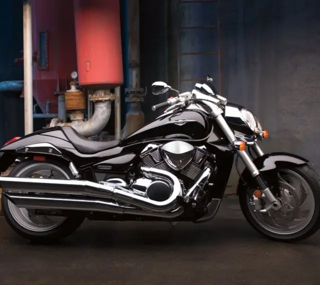 Czarny Suzuki Boulevard 1800 lśni w blasku przemysłowego otoczenia. Potężny silnik i chromowane detale przyciągają wzrok.