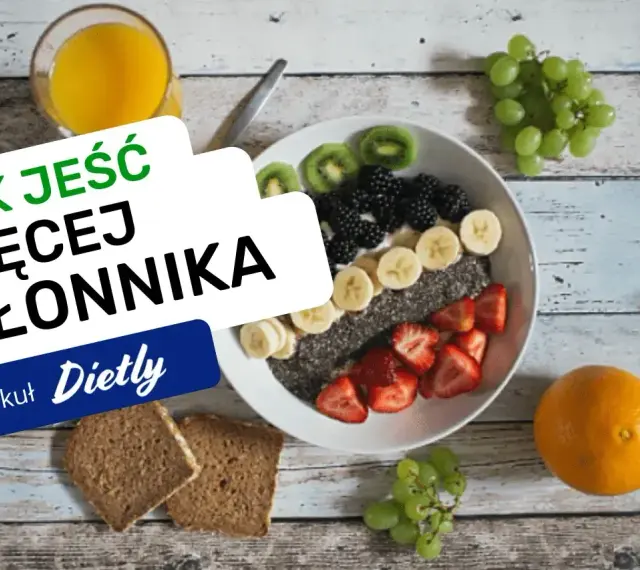 Pyszna owsianka z owocami i nasionami chia, idealna na śniadanie, które ma duzo blonnika. Obok szklanka soku i kromki chleba.
