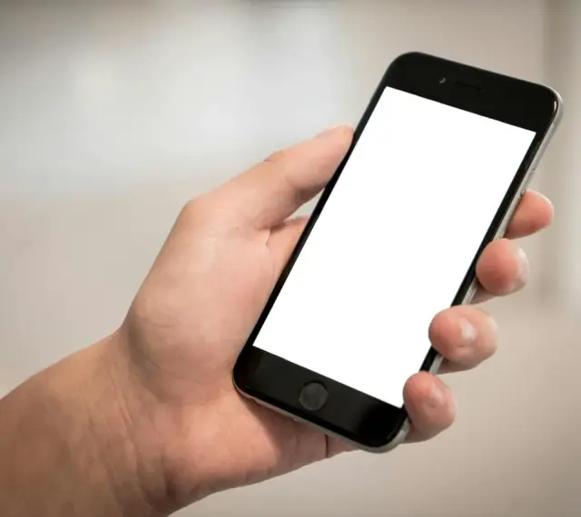 Dłoń trzyma smartfon z pustym ekranem. Cisza, brak id dzwoniącego.